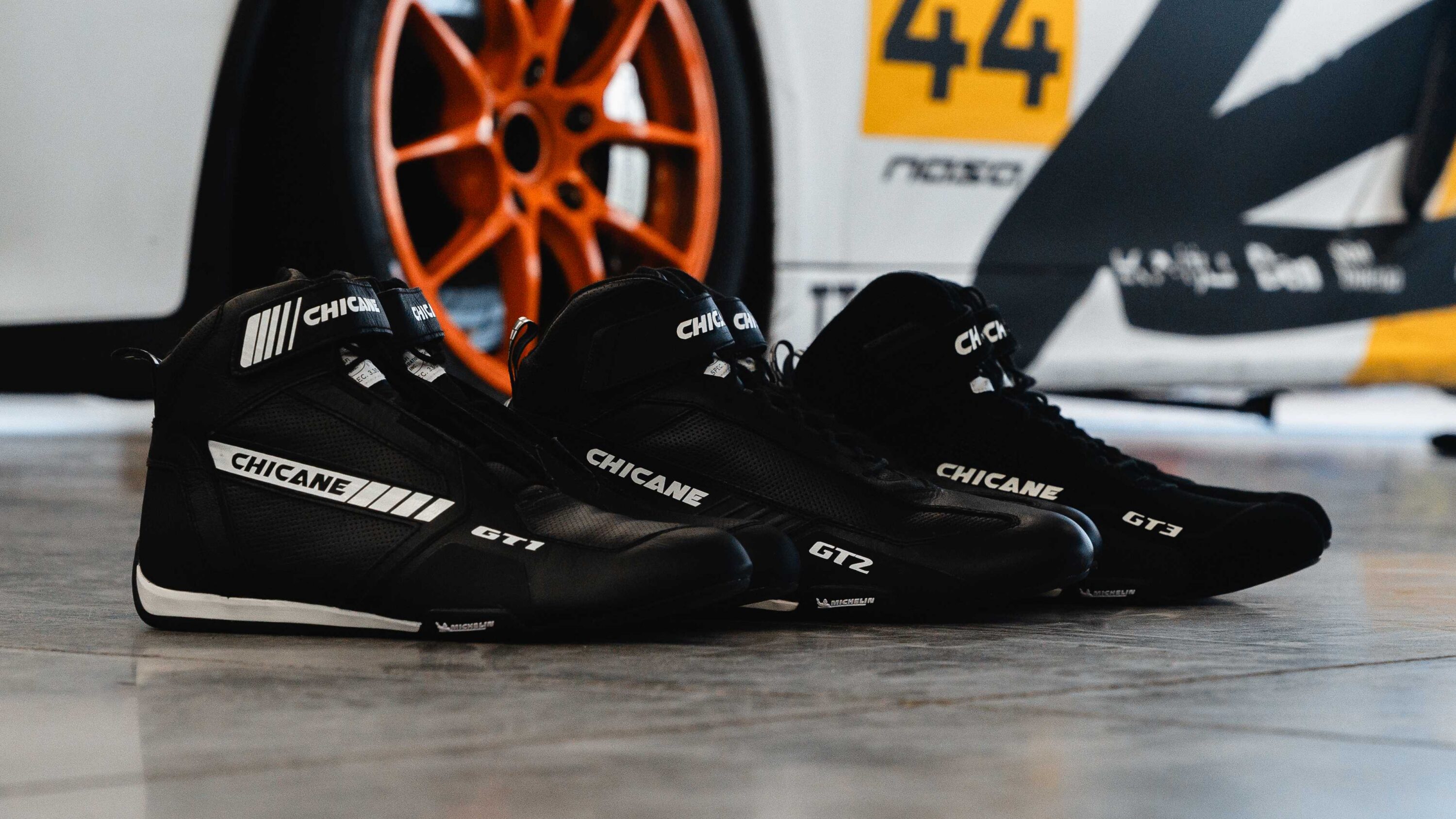 Full Chicane lineup featuring GT1 GT2 and GT3 racing shoes displayed in paddock showing evolution of LVRY performance driving footwear.