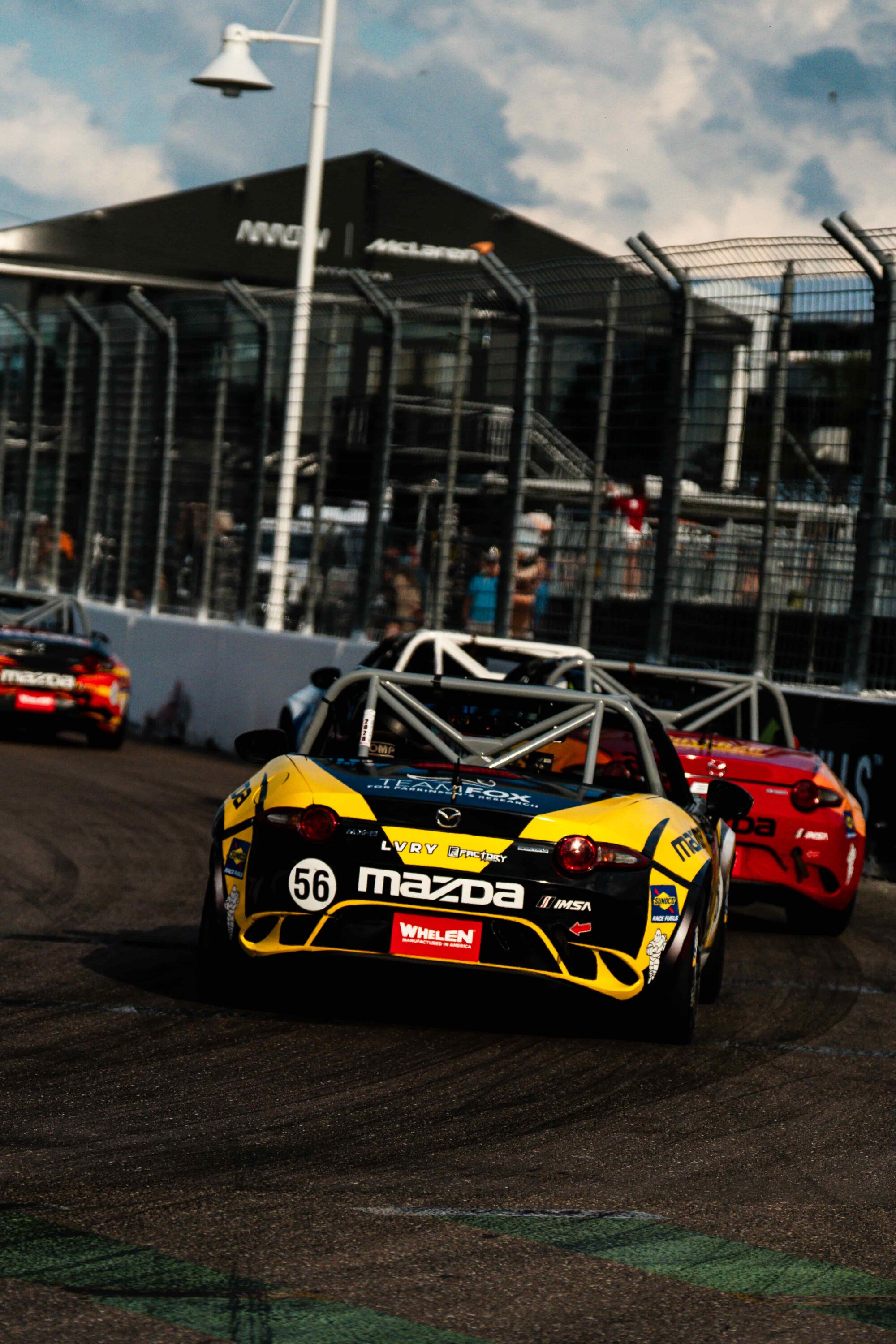 Nathan Nicholson driving the No. 56 Mazda MX-5 in the IMSA Whelen Mazda MX-5 Cup on a street circuit, battling through traffic during close spec-series racing.