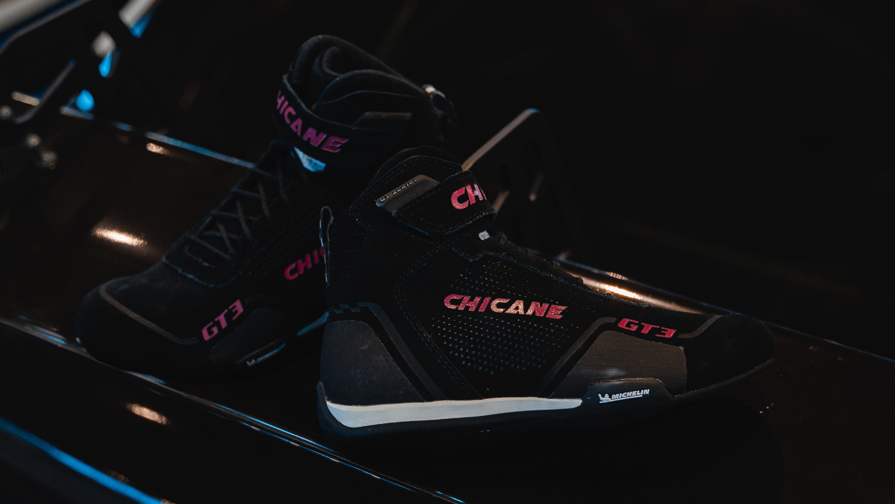 Black Chicane GT3 women’s racing shoes with Michelin sole inside race car, designed for performance and safety on track.