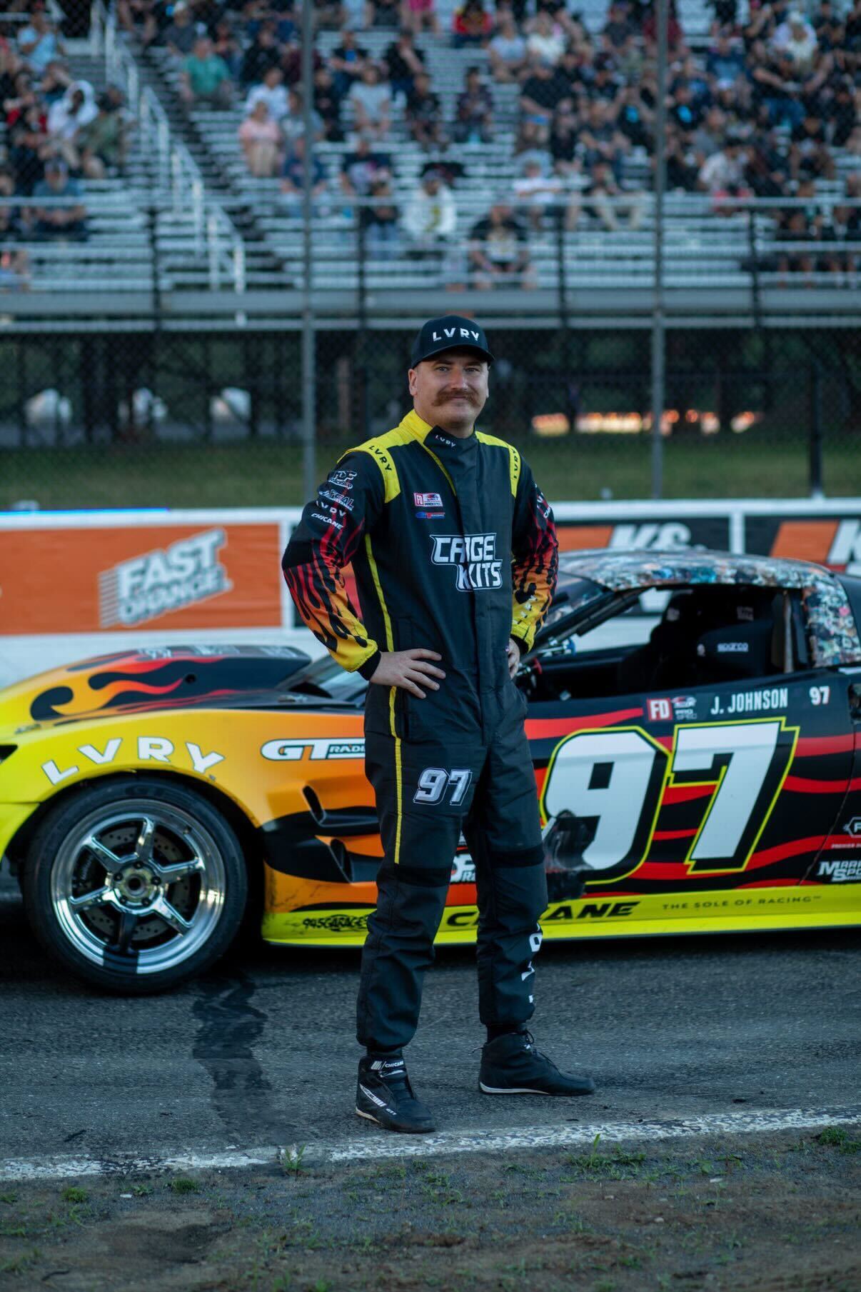 Formula Drift PROSPEC driver Jerry Johnson wearing his custom LVRY WORKS race suit in front of his number 97 flame livery drift car.